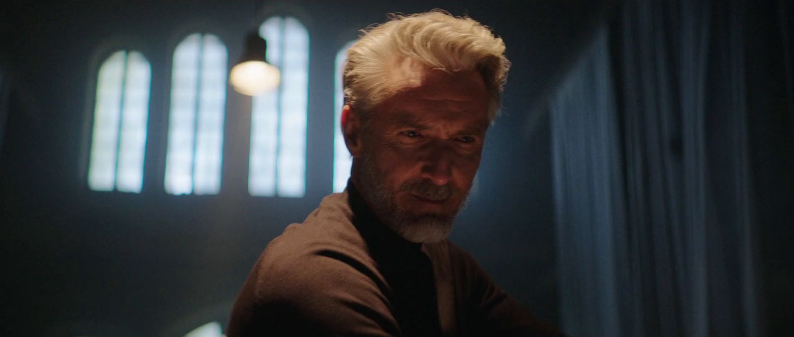 a man with white hair and a beard in a dark room