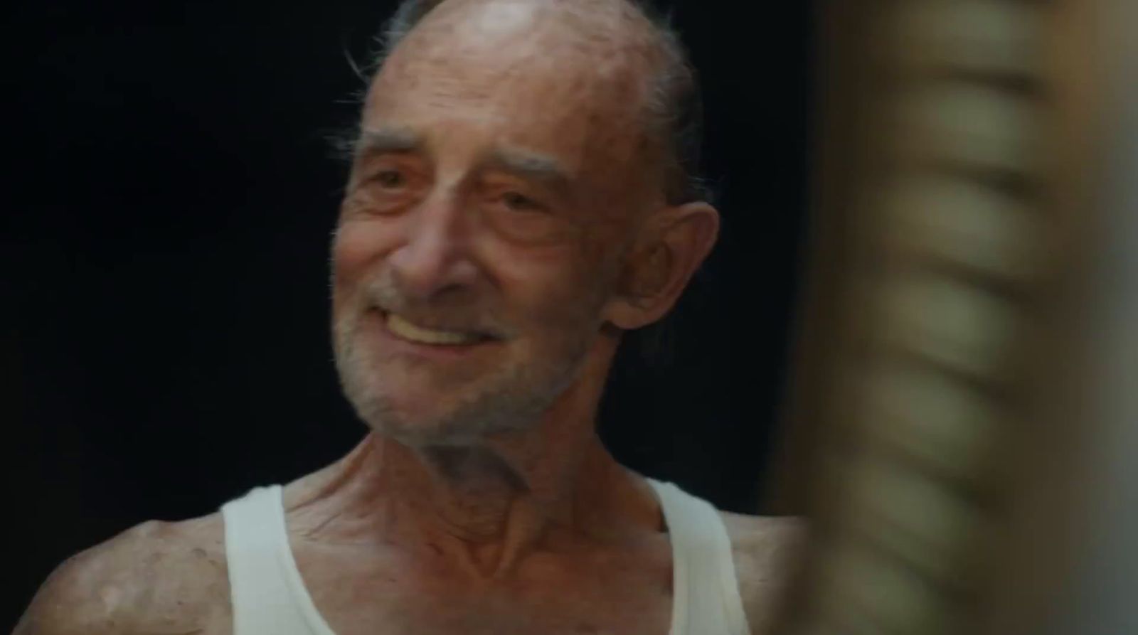 an older man with wrinkles and a white tank top