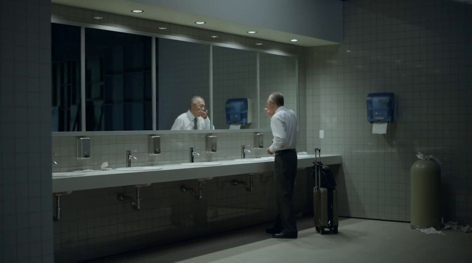 a couple of men standing in front of a bathroom mirror