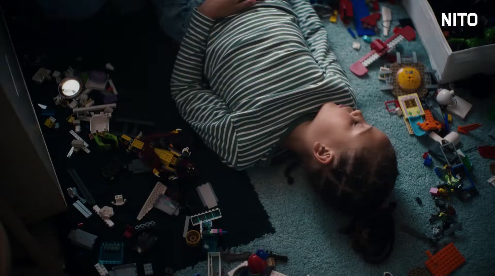 a child laying on the floor surrounded by toys