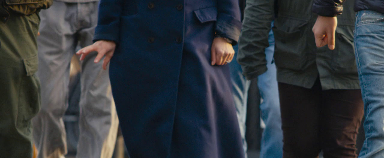 a woman in a blue coat is standing in front of a group of people