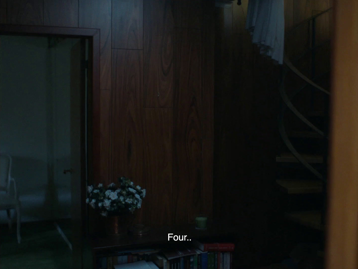 a room with a book shelf and a vase of flowers