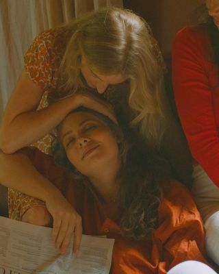 a woman laying on a bed next to another woman