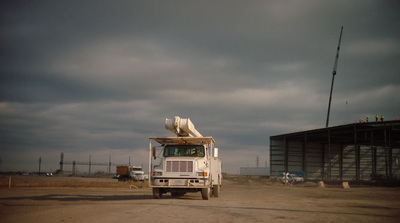 a white truck parked in front of a building under a cloudy sky