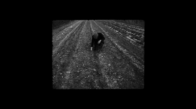 a black and white photo of a person walking in a field