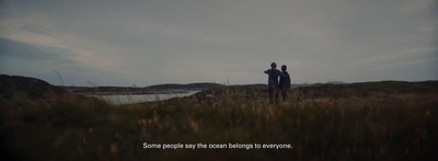 a couple of people standing on top of a grass covered hill