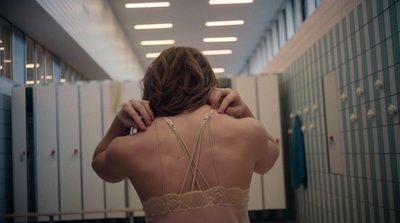 a woman standing in a locker room with her back to the camera