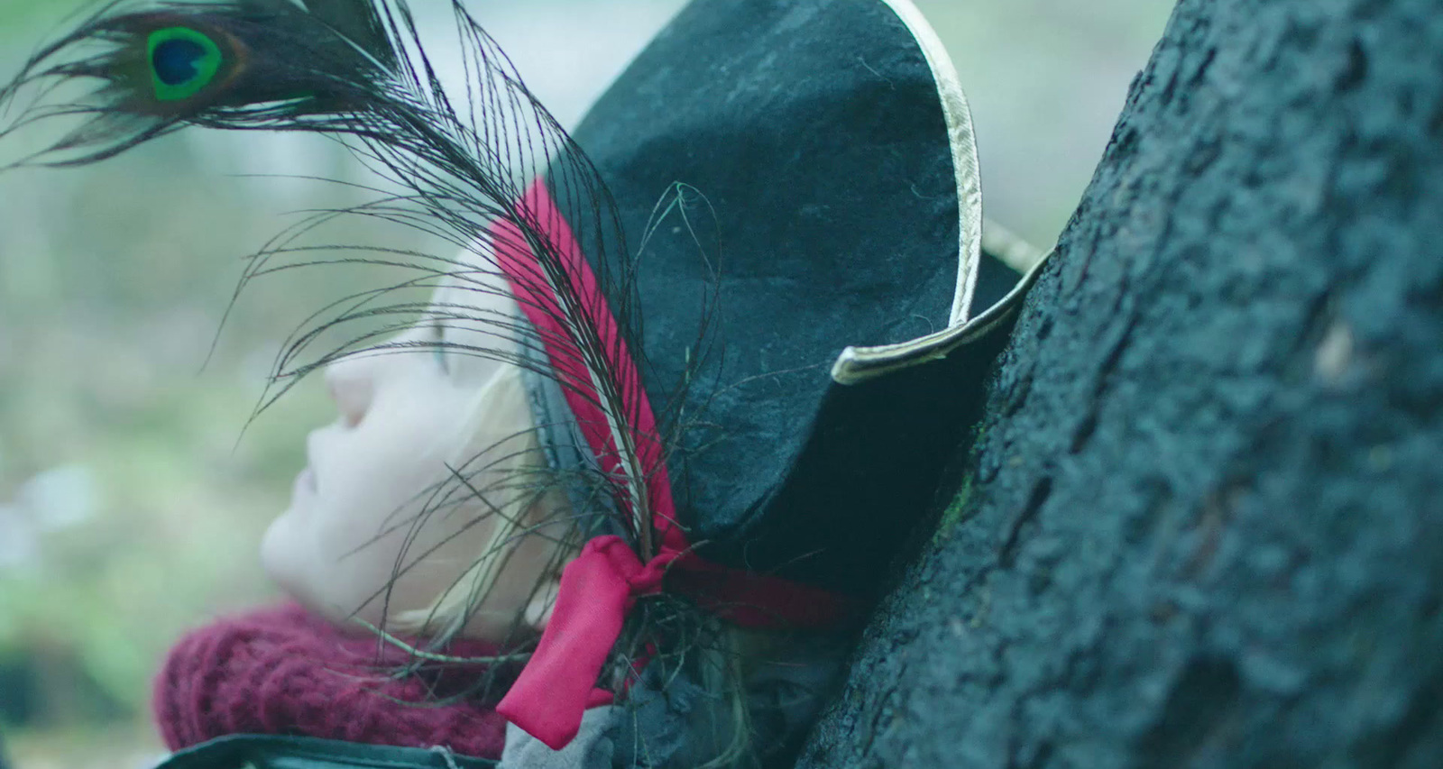 a little girl wearing a hat and a feather