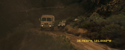 a couple of trucks driving down a dirt road