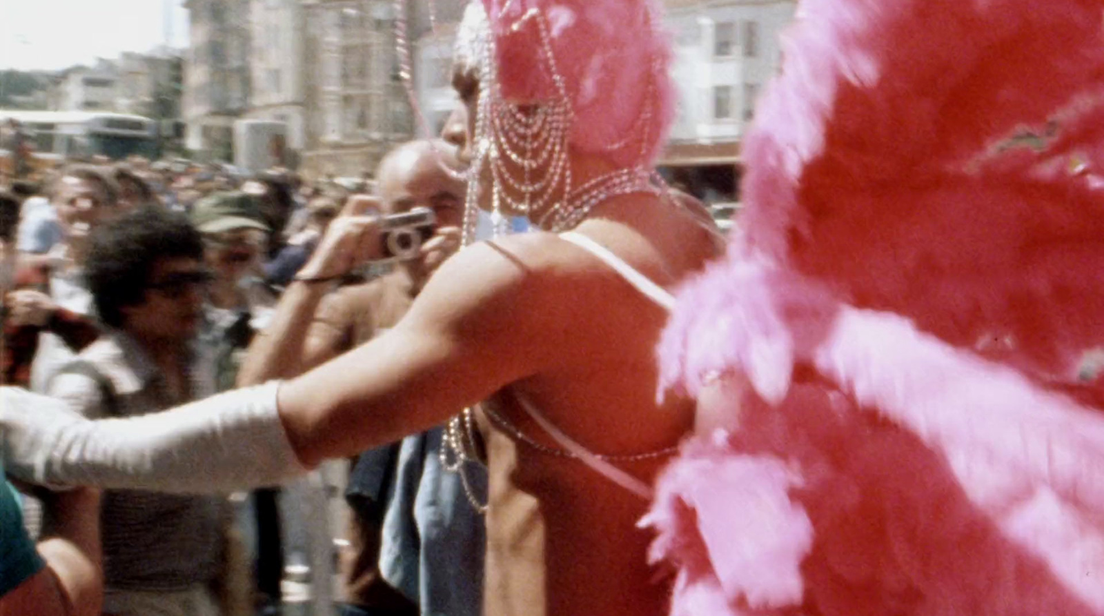 a woman in a pink feathered costume standing in front of a crowd