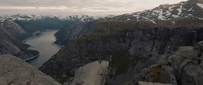 a man standing on top of a cliff overlooking a lake