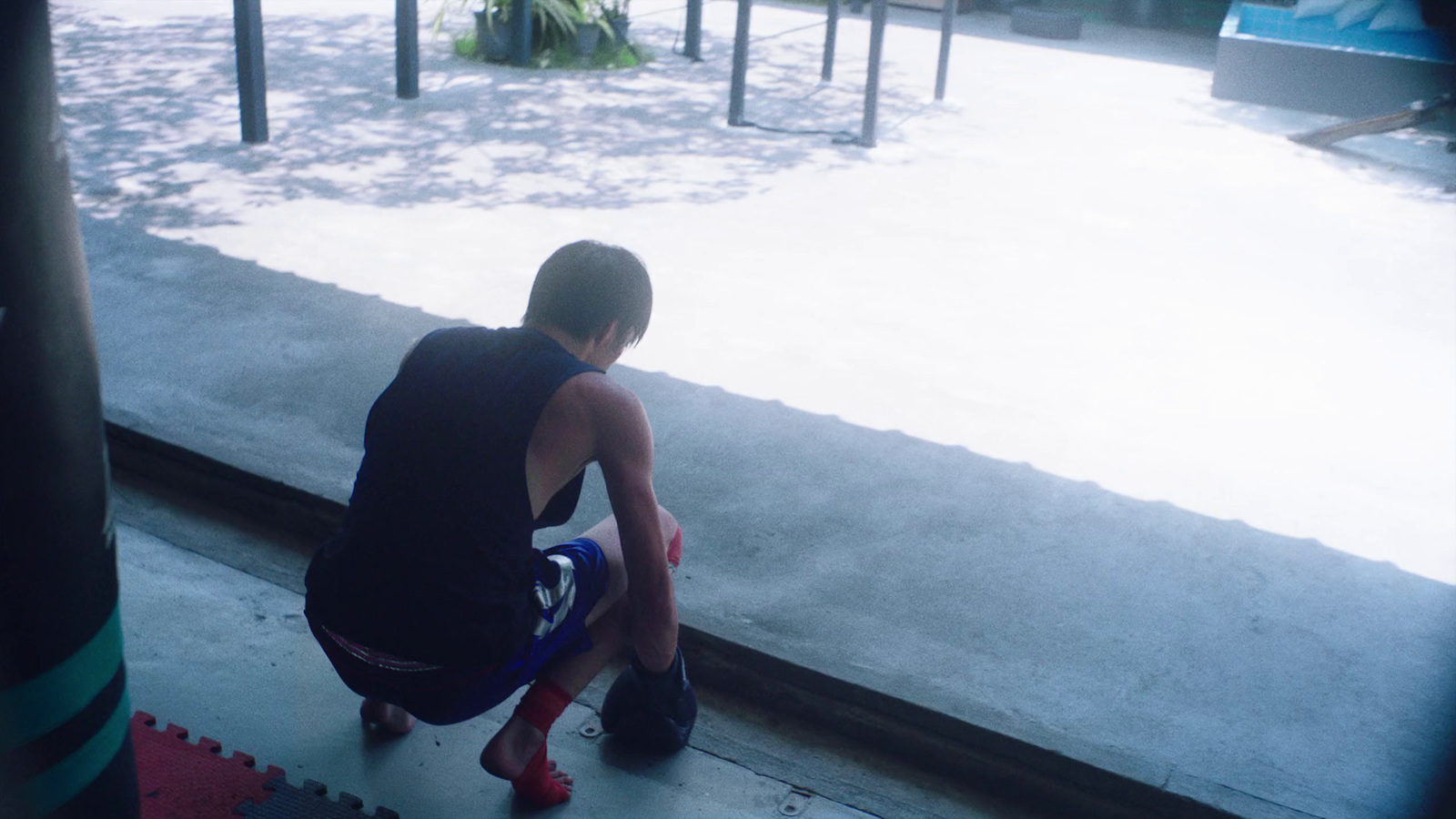 a young man sitting on the ground in front of a window