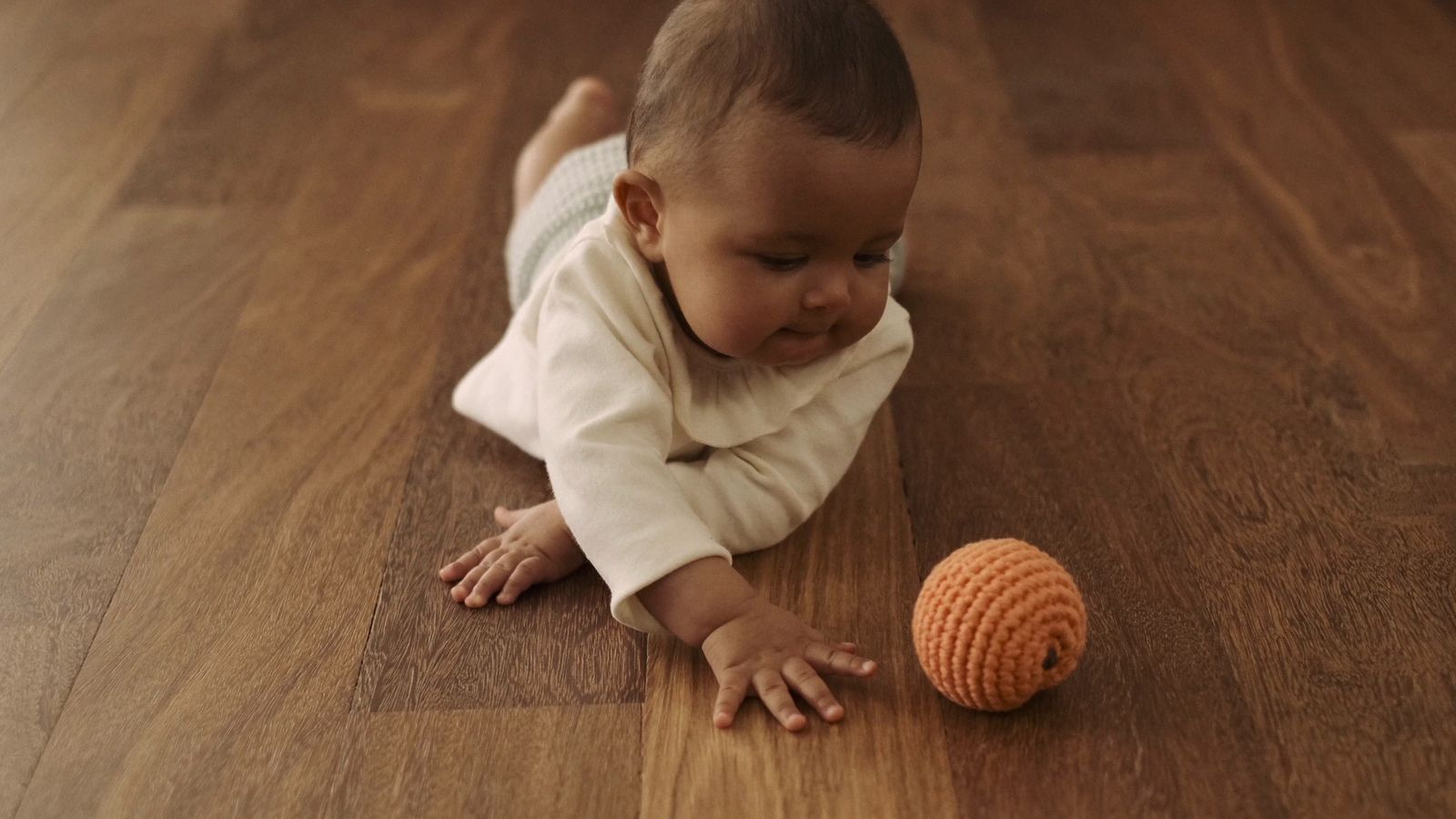 a baby playing with a ball on the floor