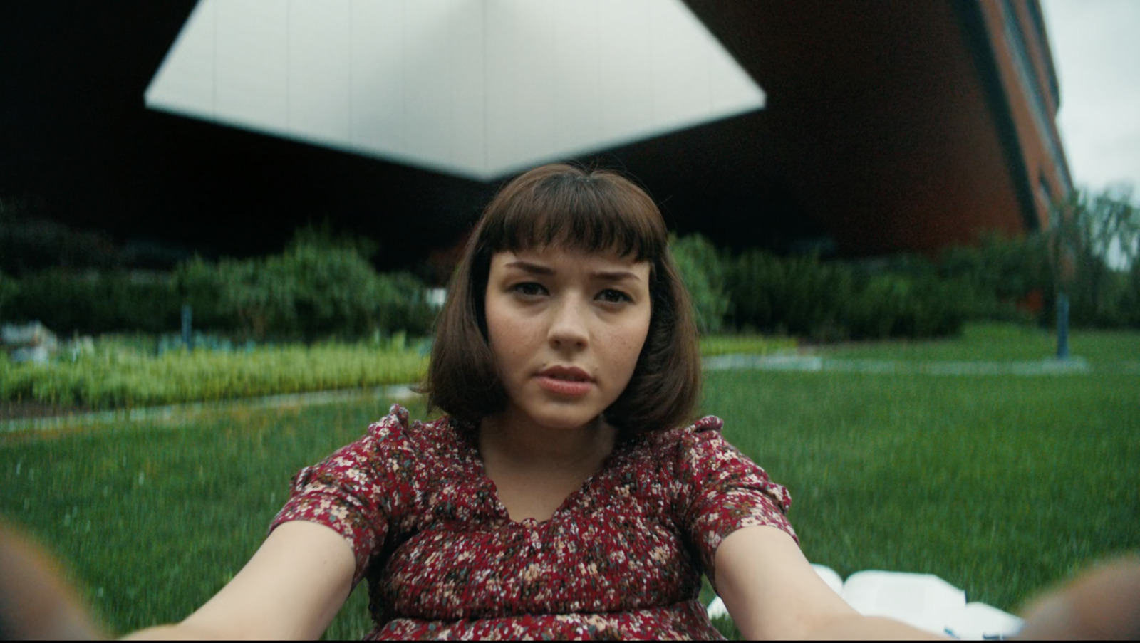 a woman sitting in the grass in front of a building