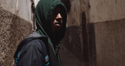 a man in a hoodie walking down a street