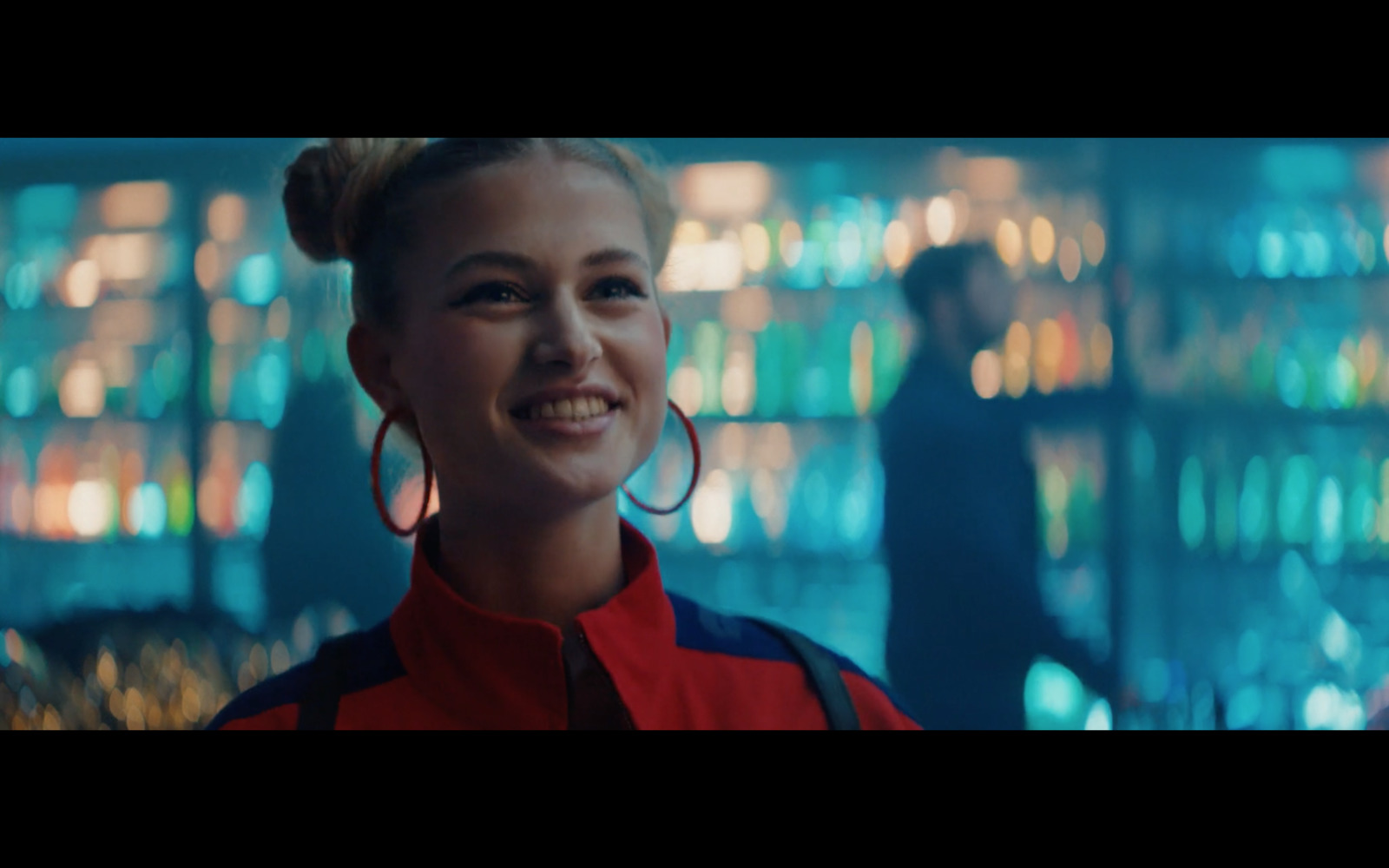 a woman with large hoop earrings standing in front of a wall of lights