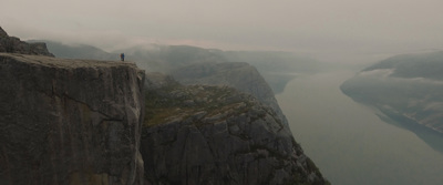 a man standing on the edge of a cliff overlooking a body of water