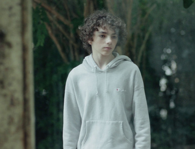 a young man standing in front of a tree