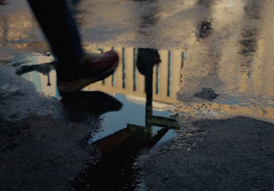 a person walking across a wet street with a parking meter