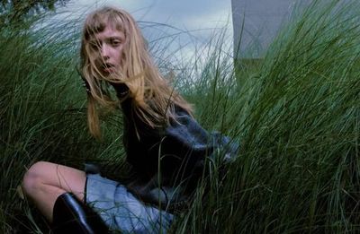 a woman sitting in a field of tall grass