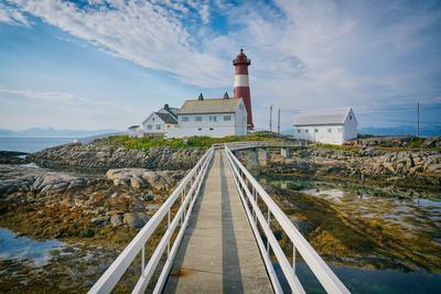 a wooden walkway leading to a lighthouse on a rocky shore