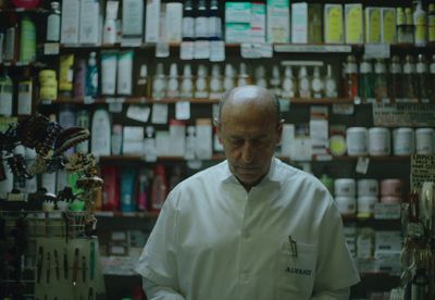 a man standing in front of a store filled with bottles