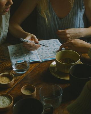 a woman sitting at a table writing on a notebook