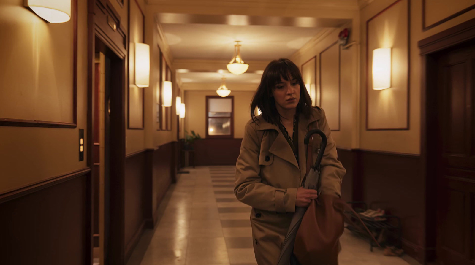 a woman walking down a hallway holding an umbrella