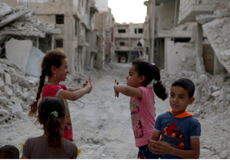 a group of children standing around a destroyed building