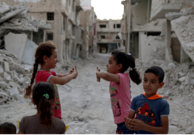 a group of children standing around a destroyed building