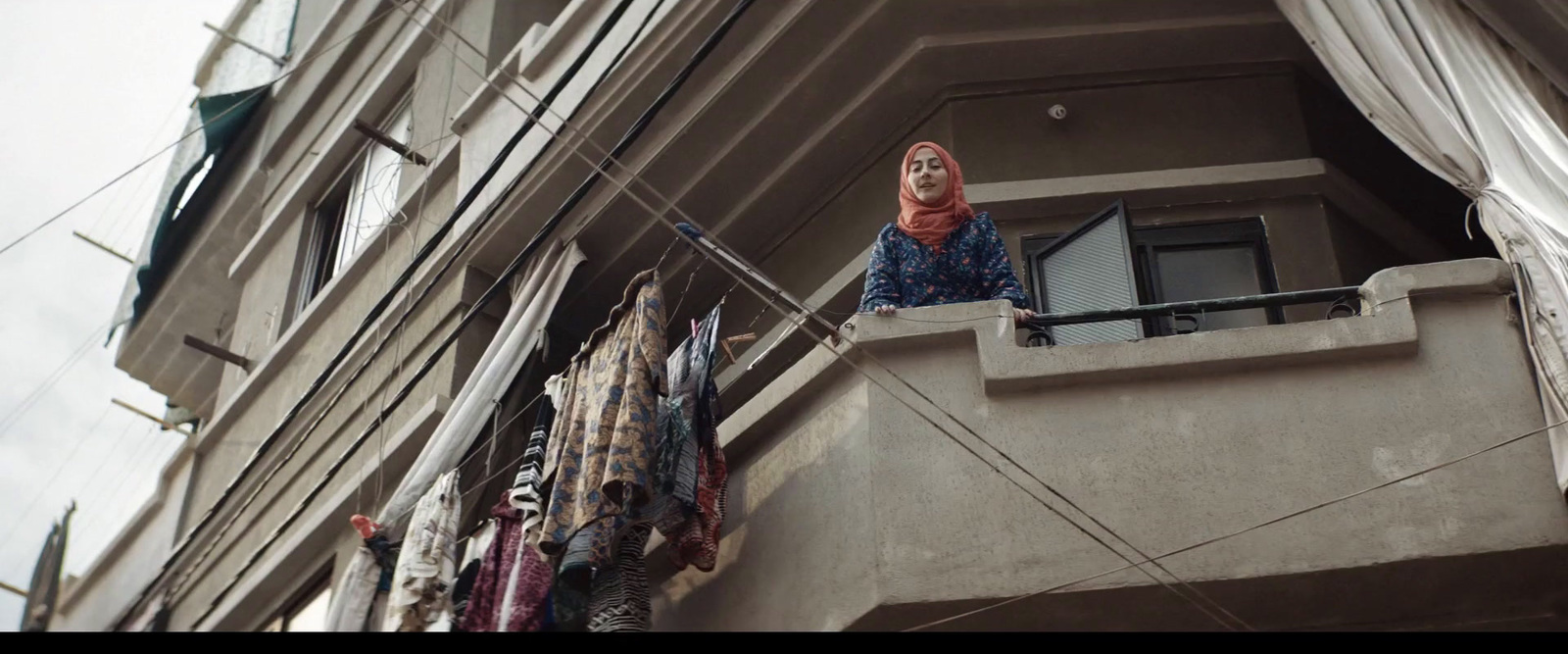 a woman standing on a balcony next to a building