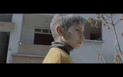 a young boy standing in front of a building