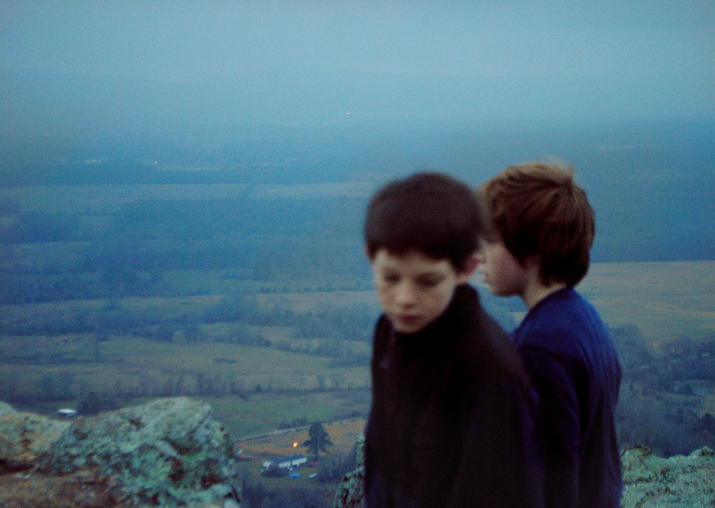 a couple of kids standing on top of a mountain