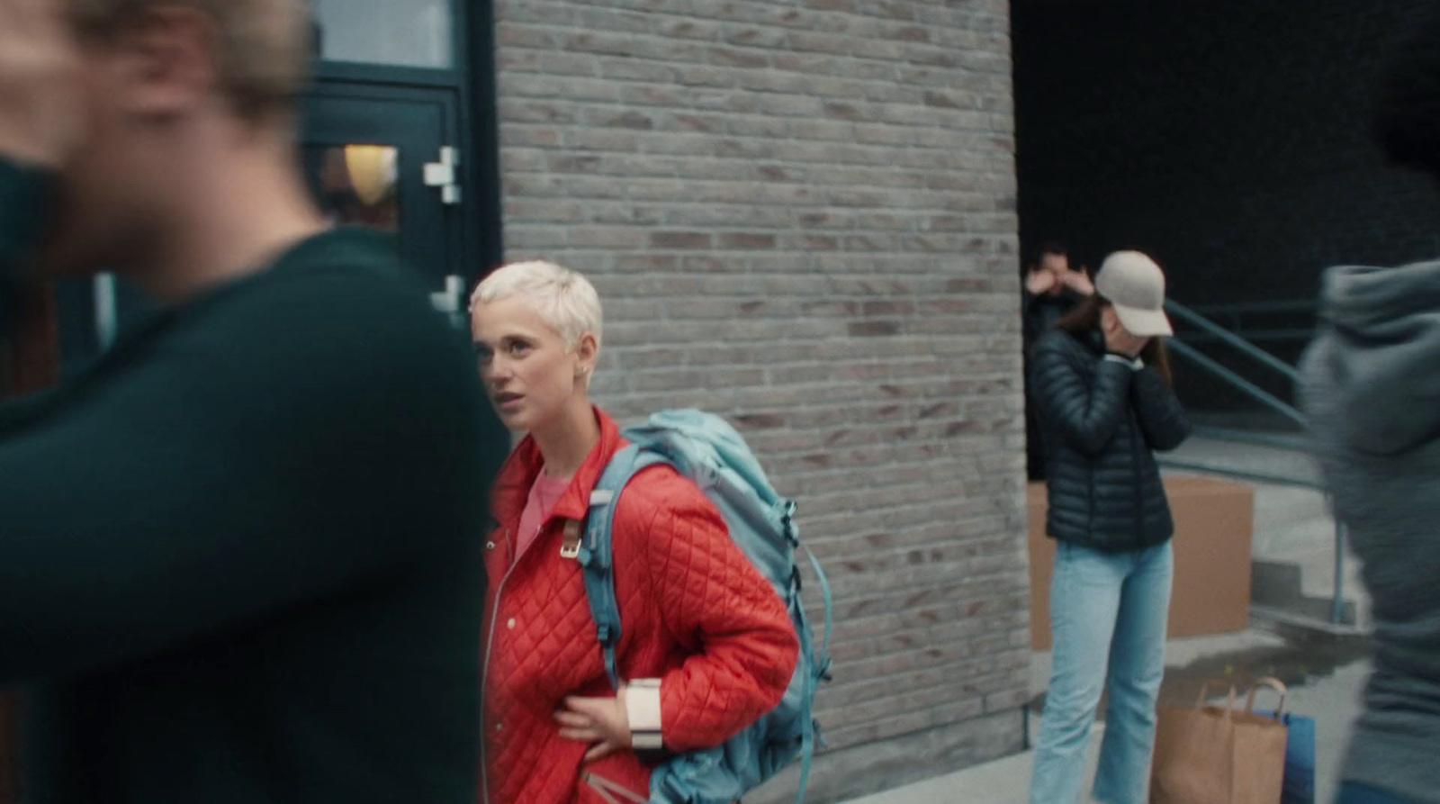 a woman in a red sweater is walking down the street