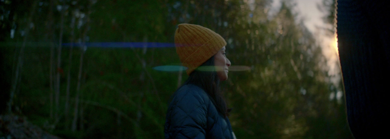 a woman wearing a yellow hat standing in a forest