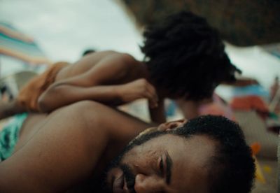 a man laying on top of a beach next to a woman