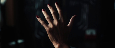 a woman's hand with red nails in the dark