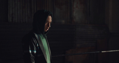 a man in a hoodie standing in a dark room