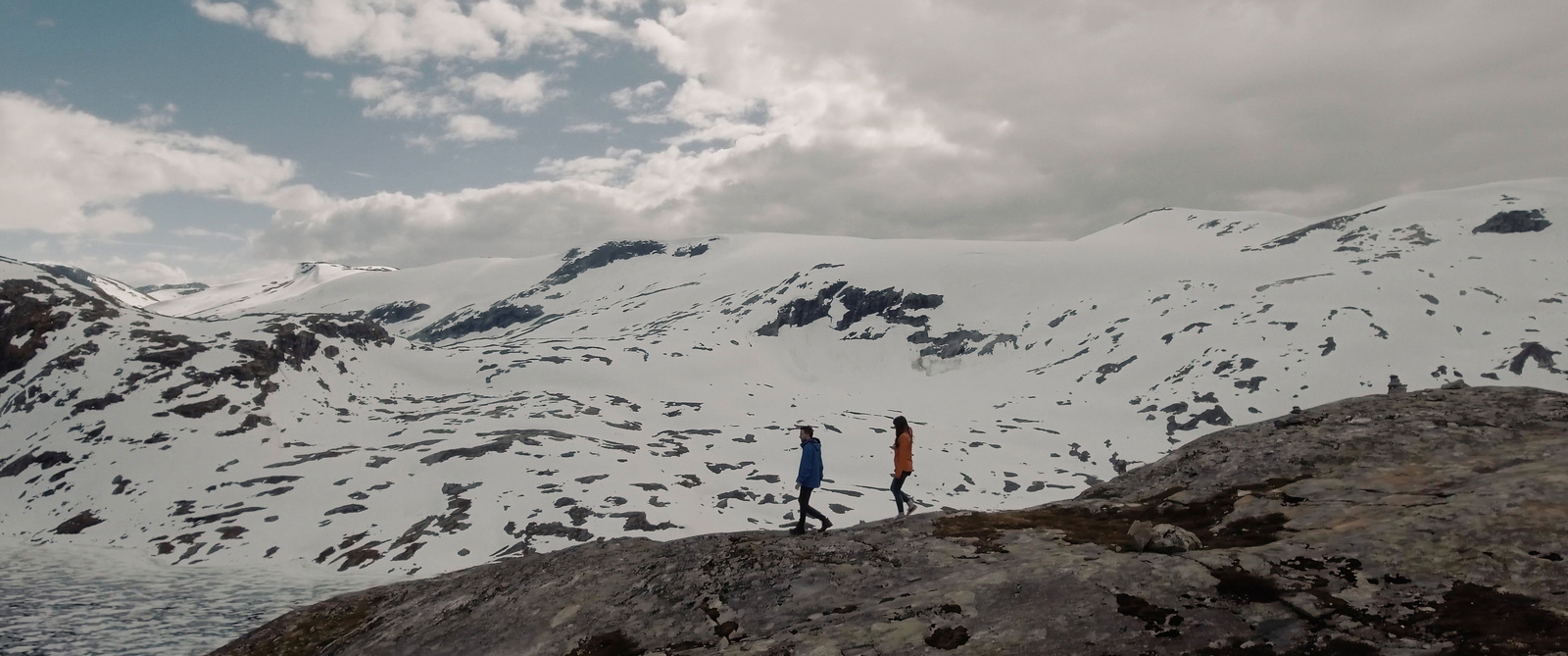 two people standing on top of a snow covered mountain