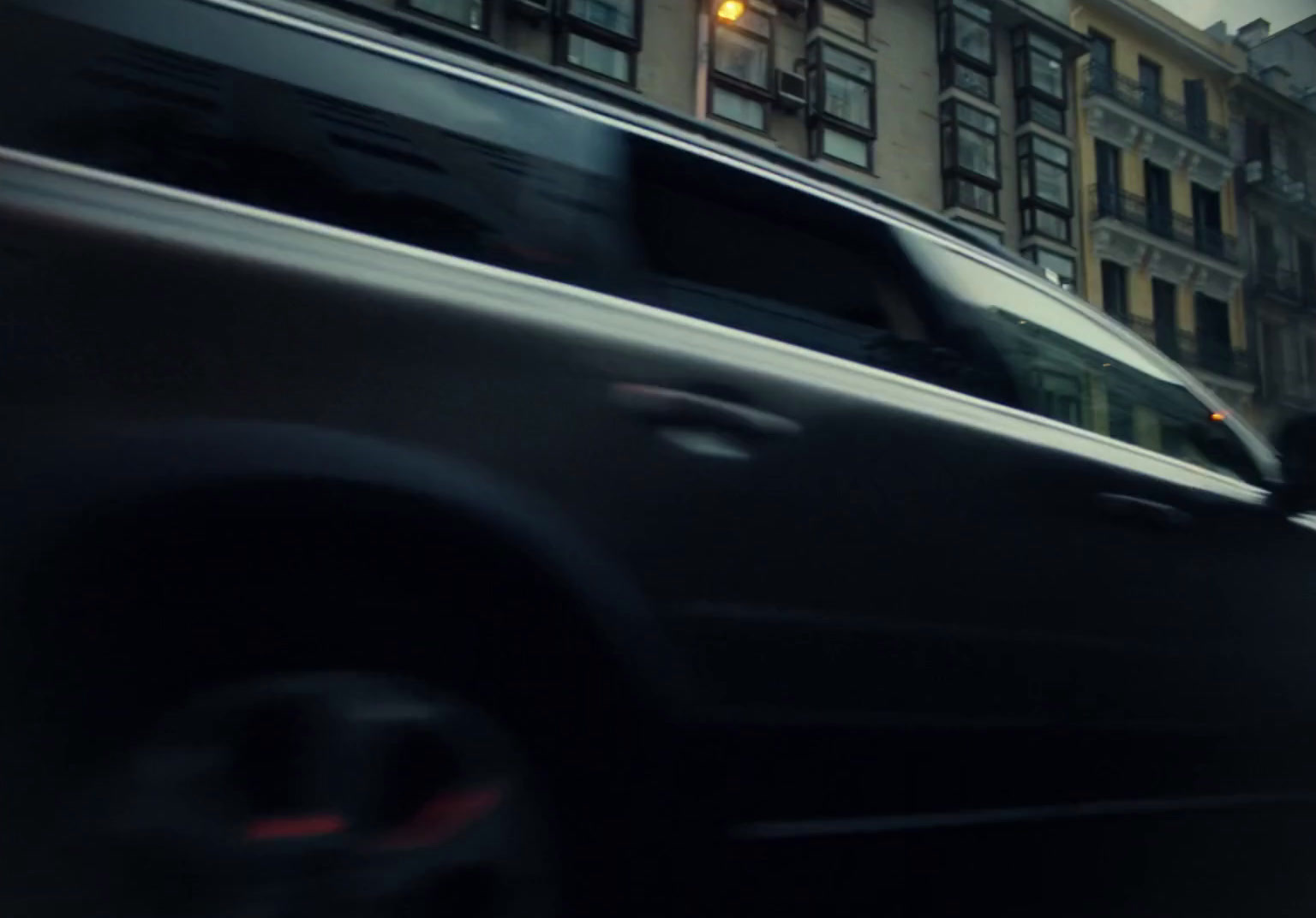 a black car driving down a street next to tall buildings