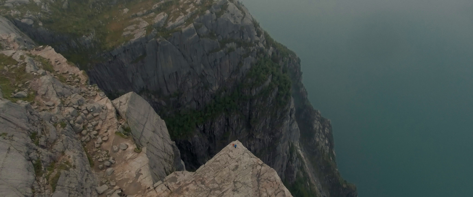 a man is standing on top of a cliff overlooking a body of water