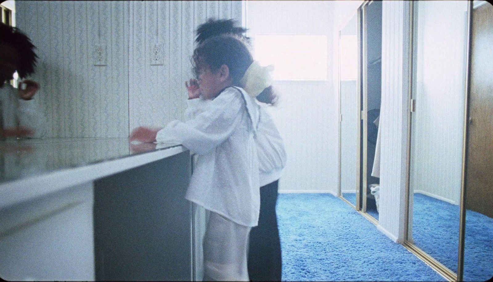 a woman standing in front of a mirror brushing her hair