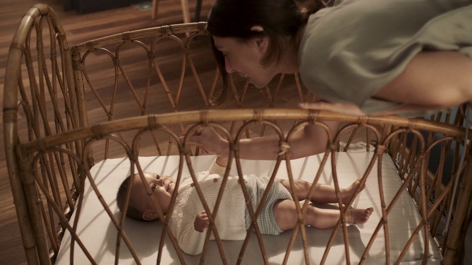 a woman bending over a baby in a crib