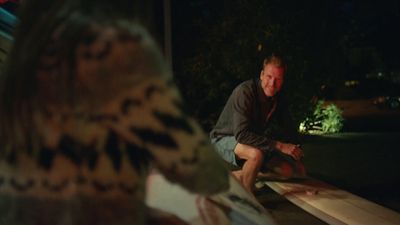 a man sitting on top of a surfboard at night