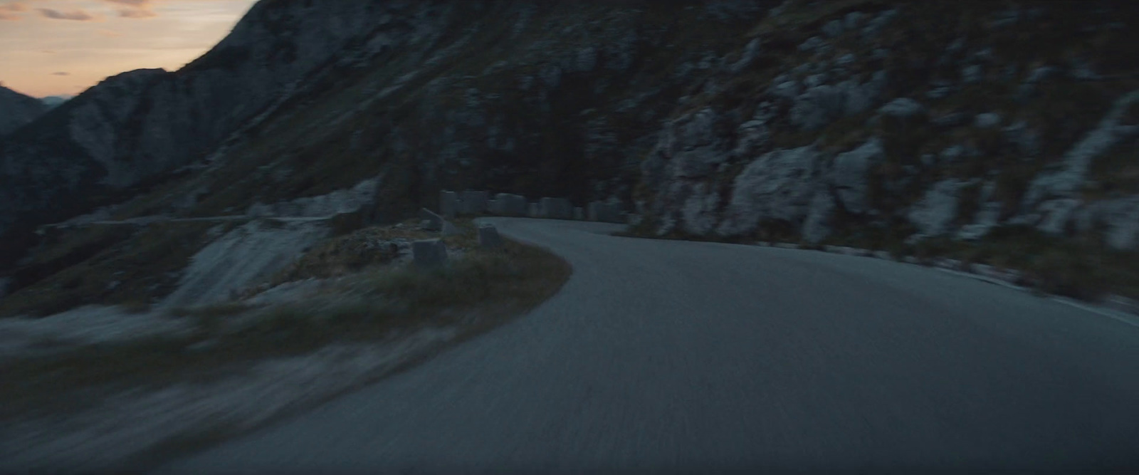 a car driving down a mountain road at dusk