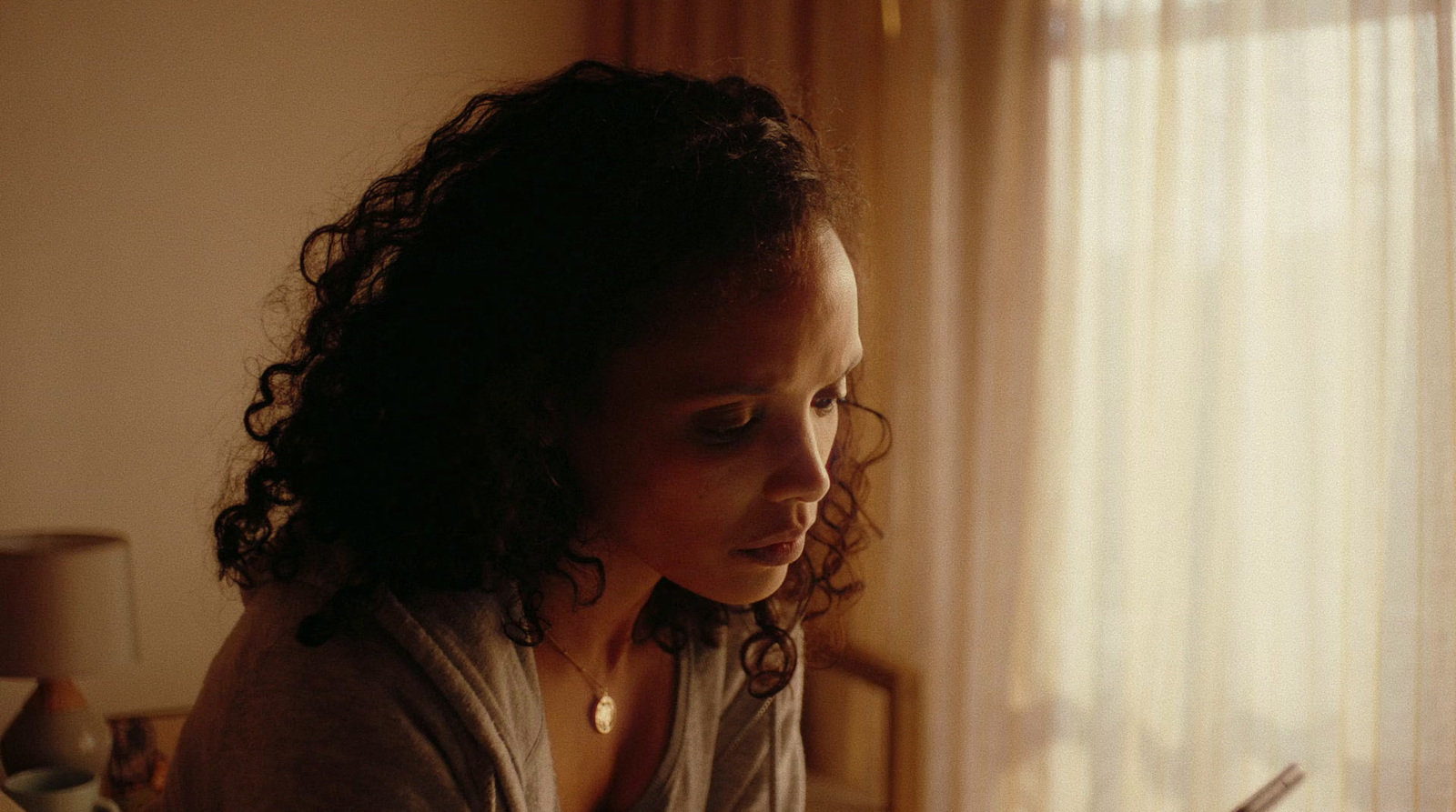 a woman sitting in front of a window looking at her cell phone