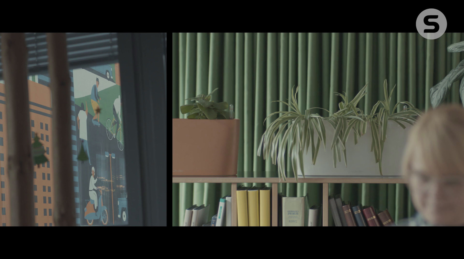 a woman looking out a window at a plant