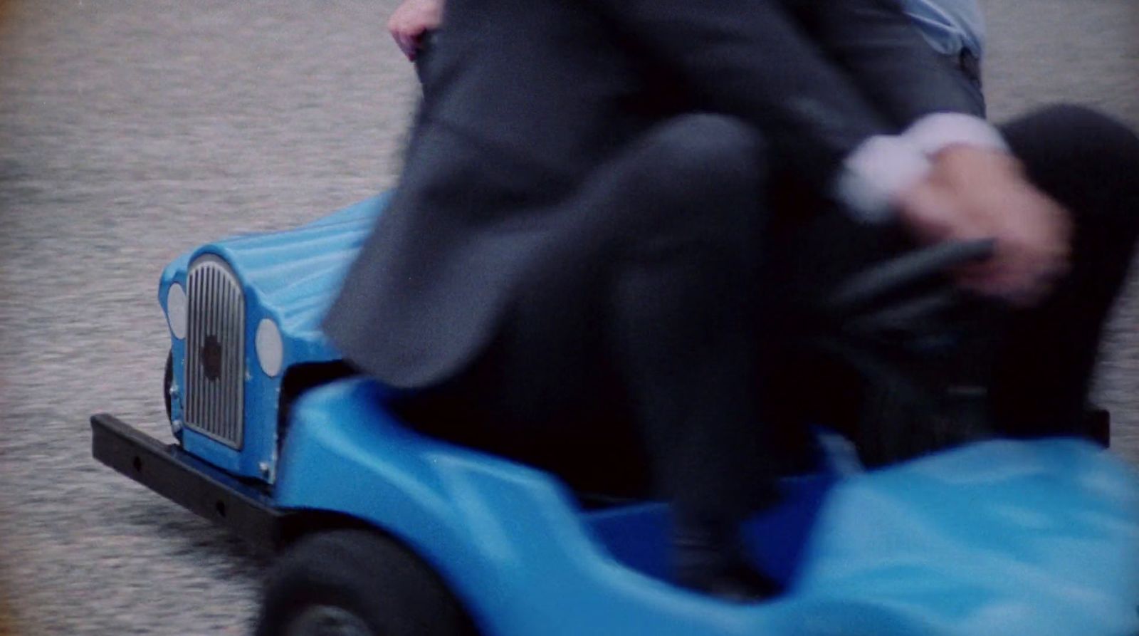 a person riding a toy car on a street