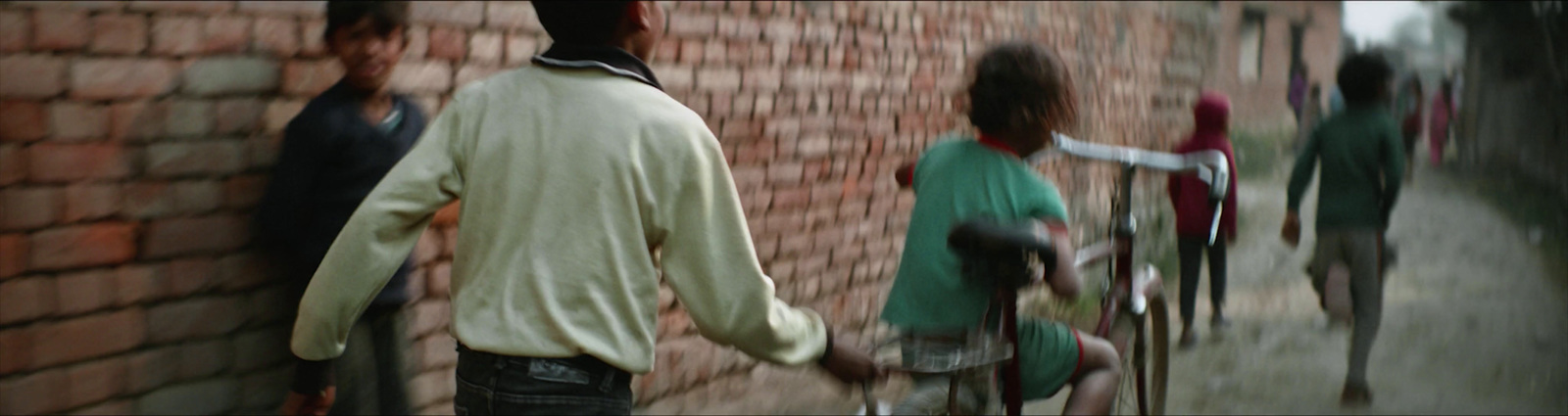 a man walking down a street next to a brick wall