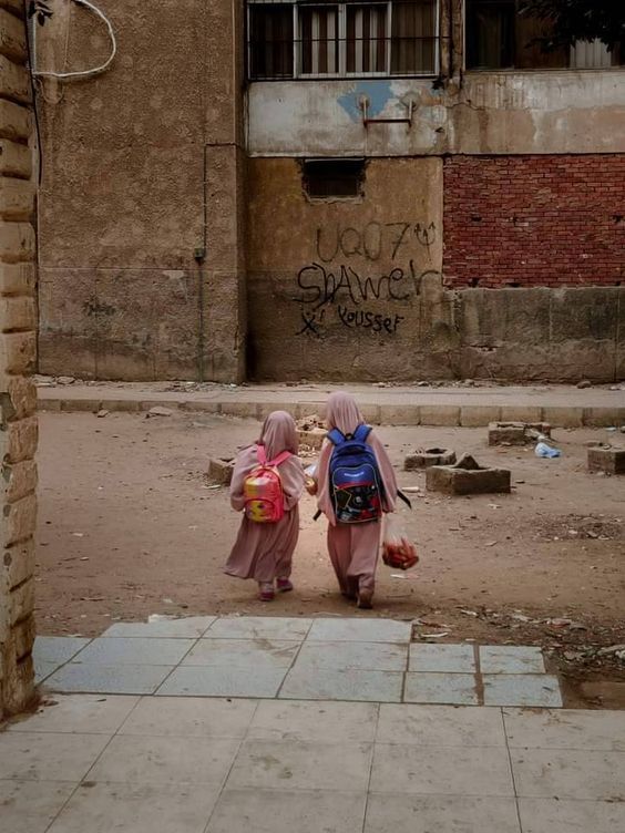 two women walking down a street in front of a building